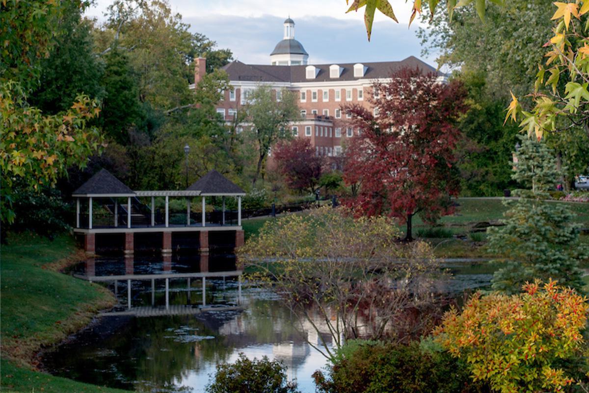 Emeriti Park at Ohio University, 校园里一个小池塘周围的秋叶, 背景是一座砖房