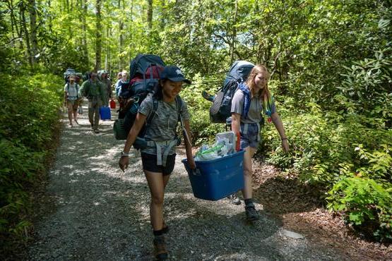 newbb电子平台的学生背着背包在森林小径上徒步旅行